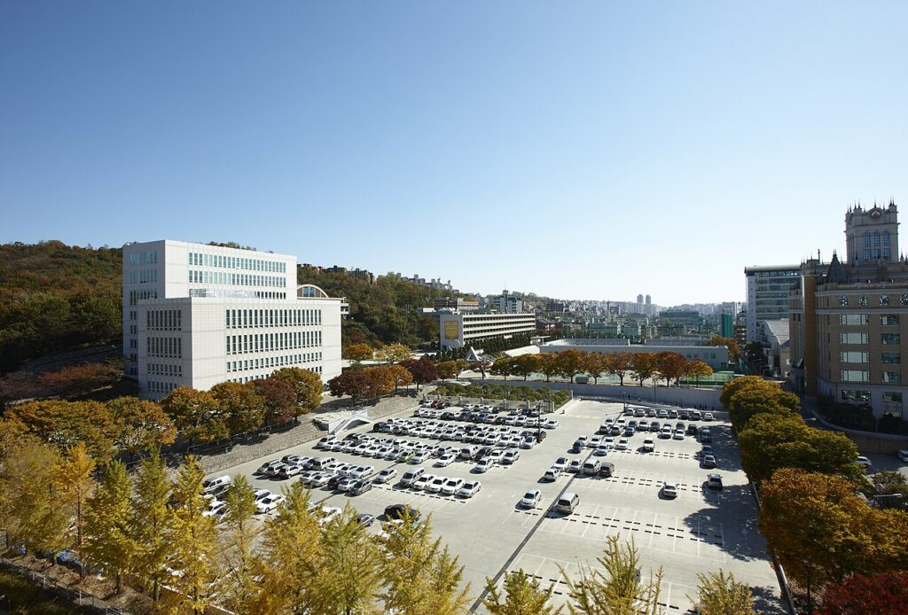 단풍 든 나무와 넓은 주차장 너머로 건물들이 보이는 서울사이버대학교 전경