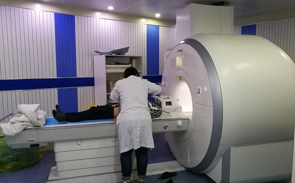 MRI 장비 앞 검사대에 누운 환자의 자세를 조정하는 의료진