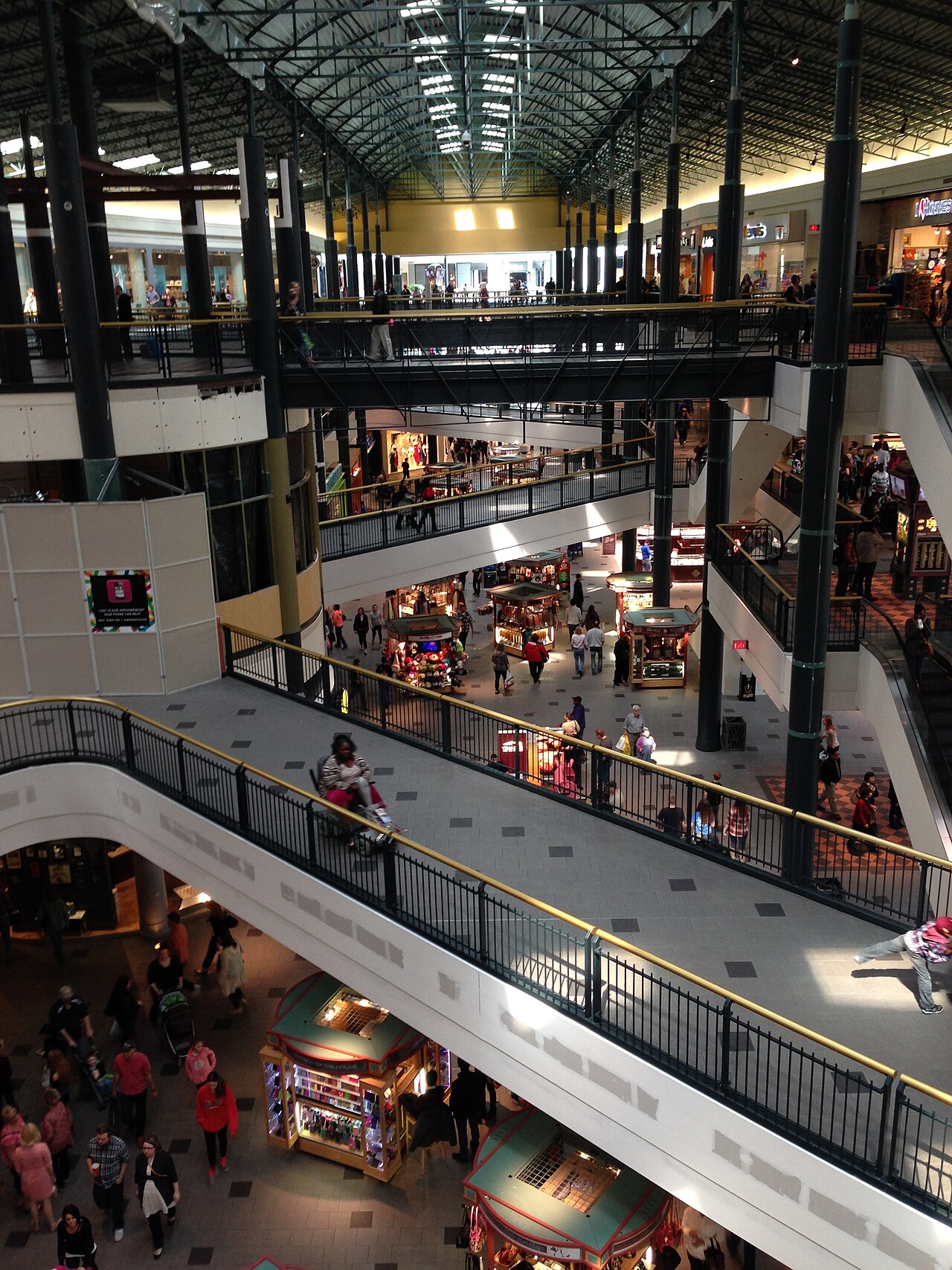 Mall of America 내부의 여러 층에 걸친 난간 통로와 에스컬레이터, 매대 주변을 오가는 사람들